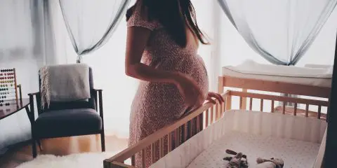 soon to be mum standing next to the baby crib