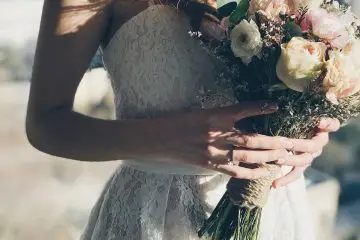 Bride holding beautiful natural flowers in her hand with a lace wedding dress