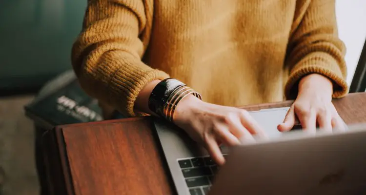 woman working on laptop and wearing yellow jumper
