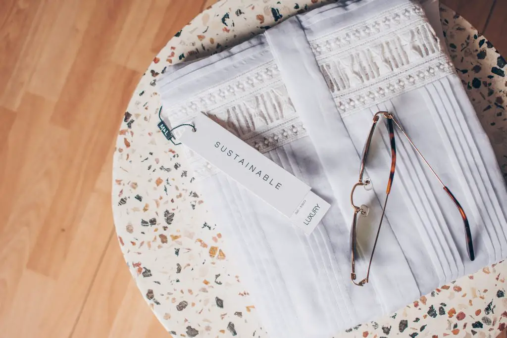 Sustainable fashion: sunglasses sitting on folded white shirt, on top of terrazzo side table