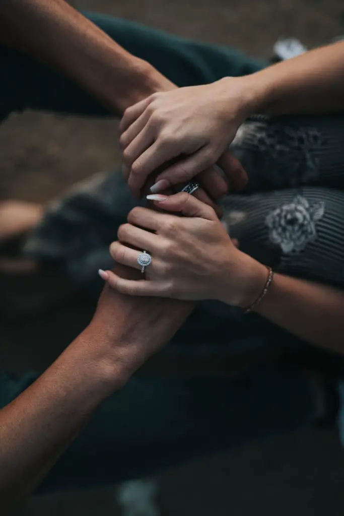 couple holding hands with woman wearing an circle engagement ring