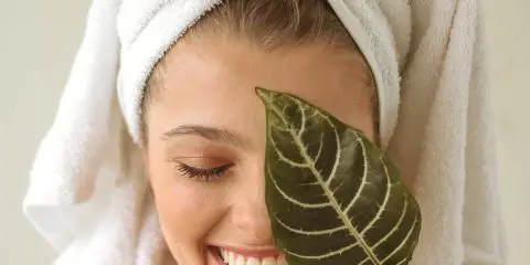 woman holding a leaf to her face wearing a bath robe