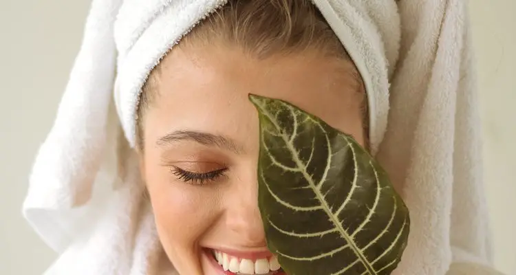 woman holding a leaf to her face wearing a bath robe