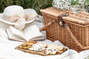 wicker picnic basket and cheese board on the grass