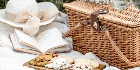 wicker picnic basket and cheese board on the grass