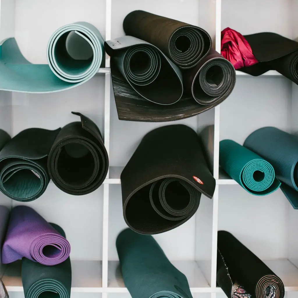 different shape and size yoga mats on a gym rack