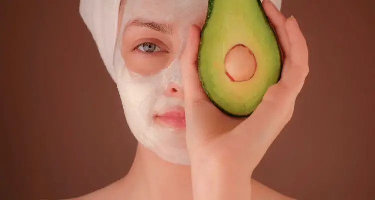 woman wearing a face mask and holding an avocado